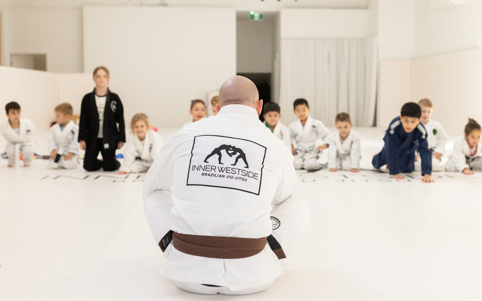 Coach John-Henry Mallam kneeling in front of the kids class